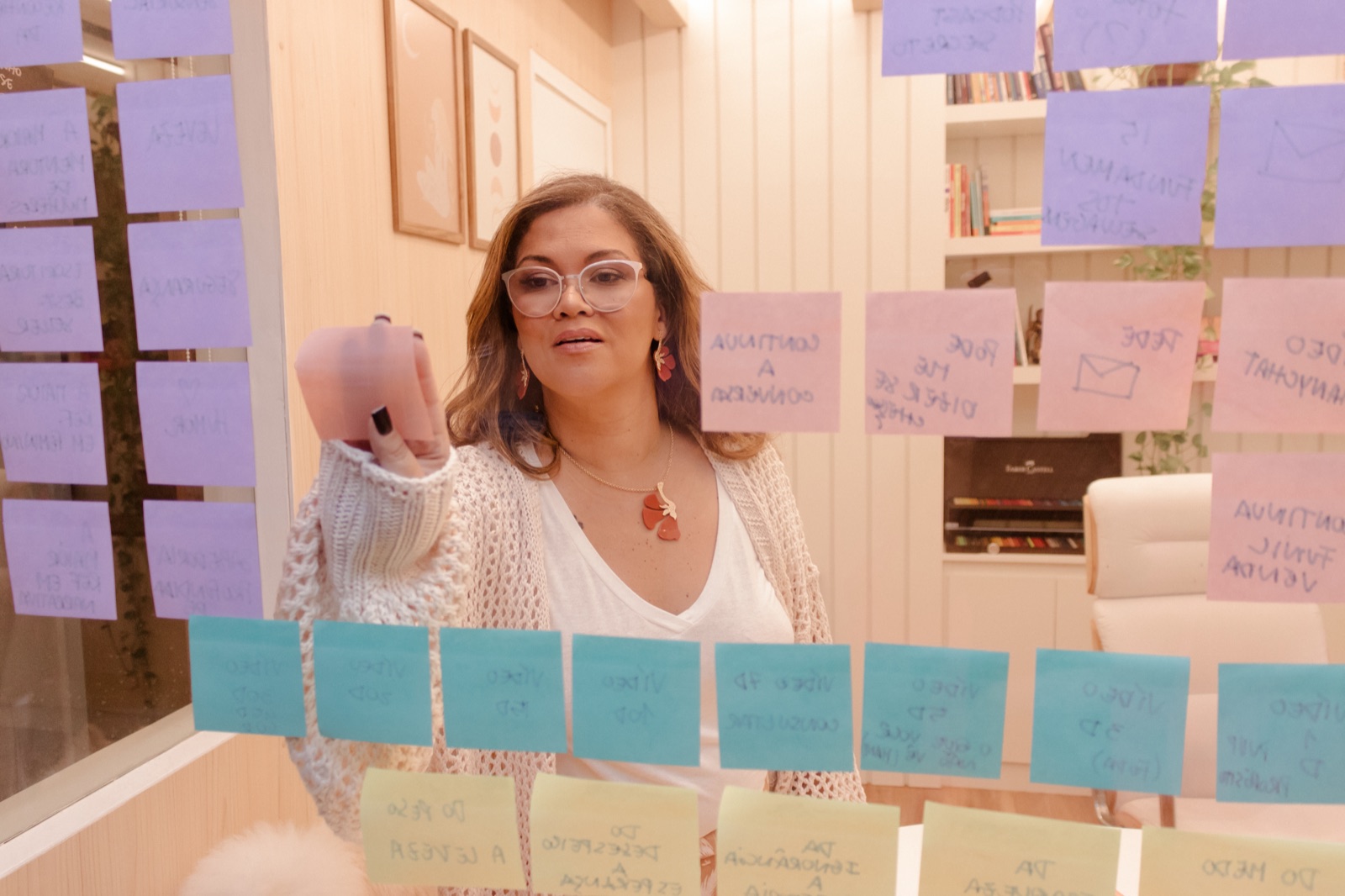 Isa Moreira planejando com notas adesivas em um painel de vidro